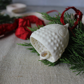 White textured ornament with a small flower on a green leafy background