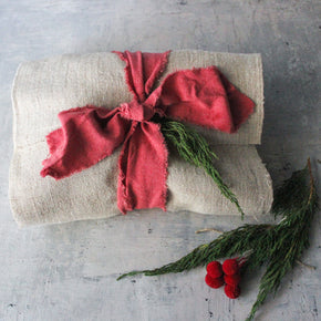 Gift wrapped in beige paper with a red ribbon on a textured surface